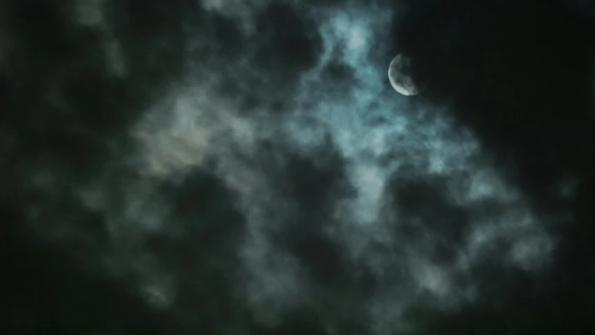 an airplane flying in the cloudy sky with a half moon