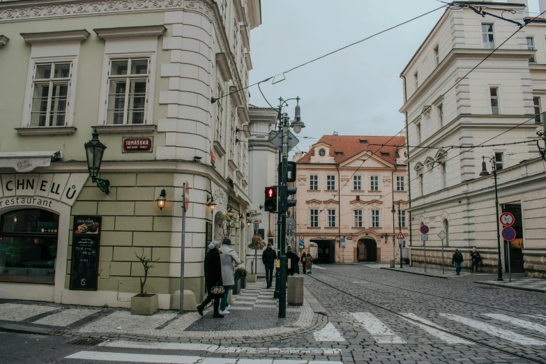 people are crossing the street in front of several old buildings