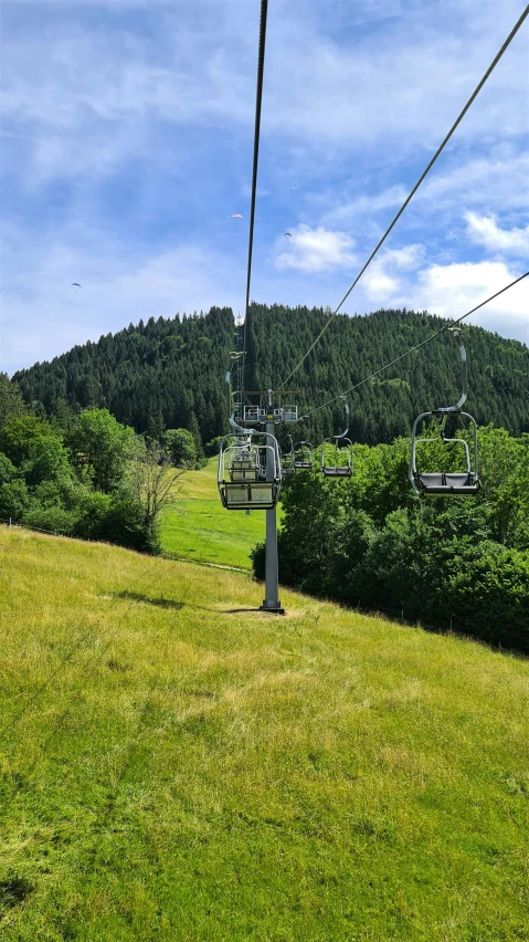 a view from the top of a lift that is suspended over a lush green hill