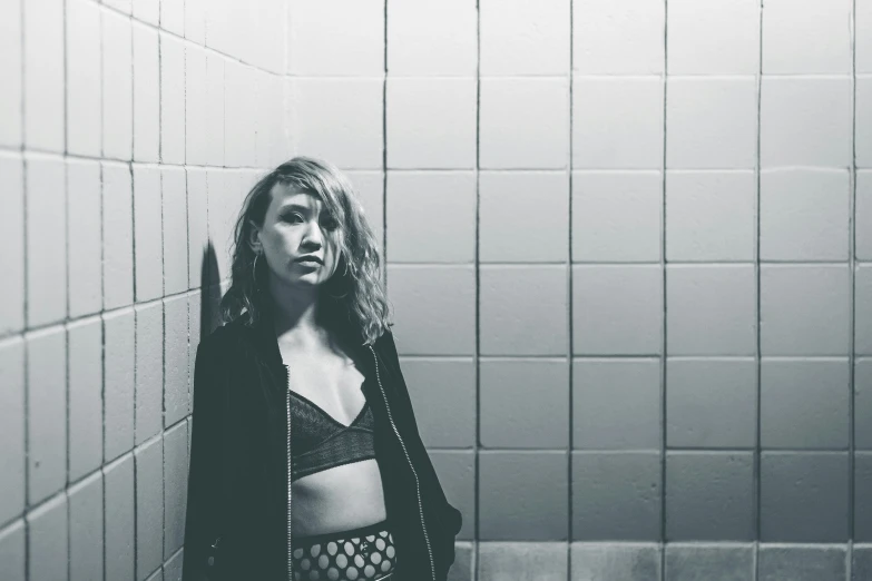 a woman leaning against the wall in a bathroom