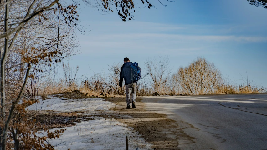 a man is walking down the road on a cold day