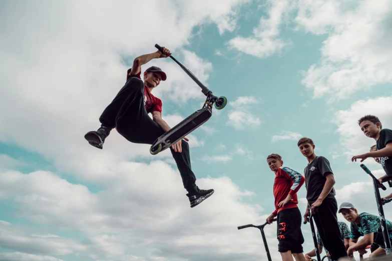 a boy on a skateboard does an aerial trick while other boys watch