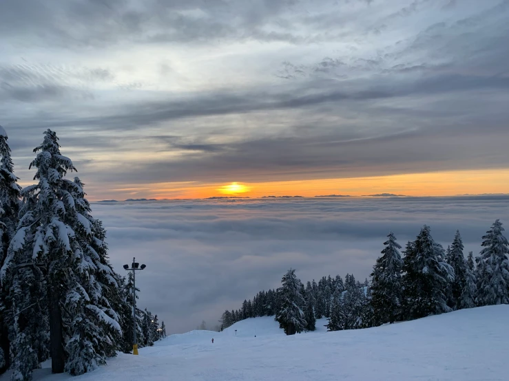 the sun is setting as seen from a snow covered hillside