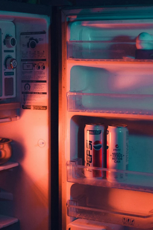 two soda cans are sitting in a refrigerator