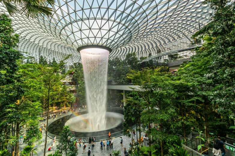 the interior of a building with lots of greenery and a water fall