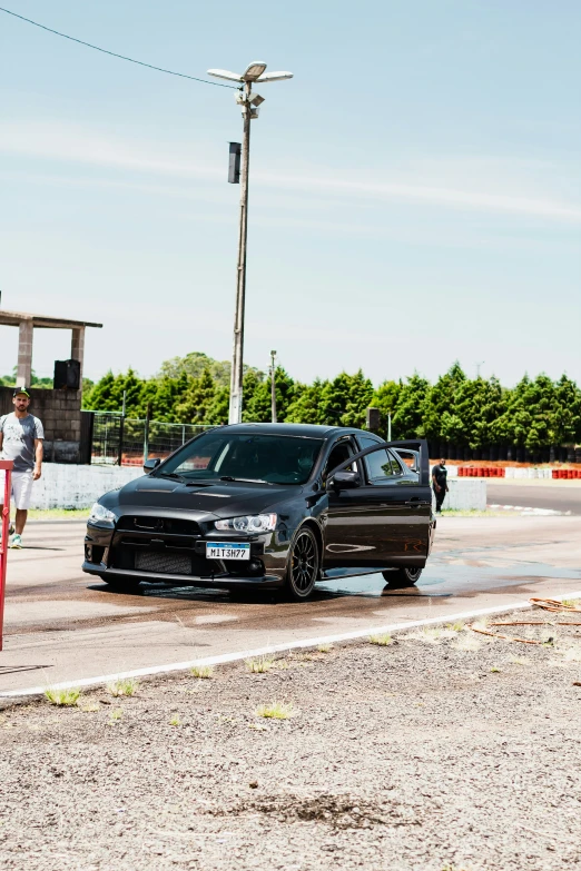 a black car parked by a road on top of the grass