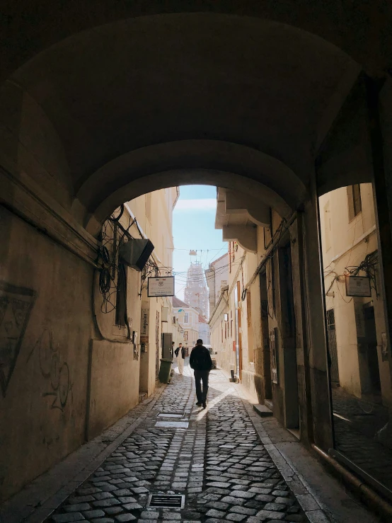 man walking down a street between two buildings