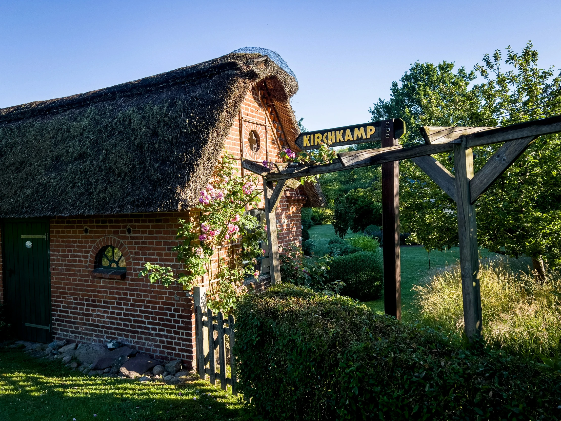 an old thatched - top building with some green plants