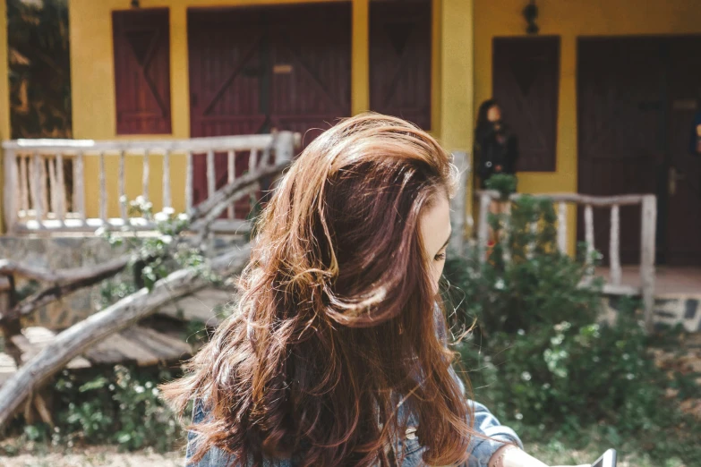 a girl holding an object while she looks at the ground