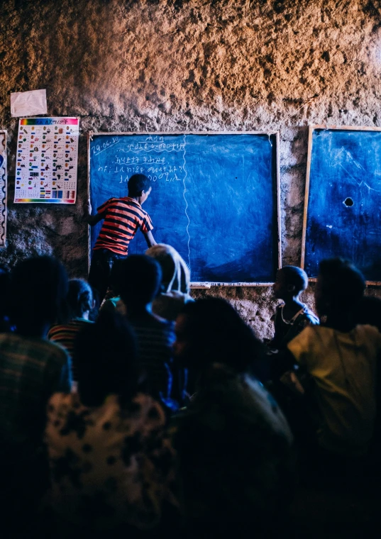 a person drawing on a chalkboard in front of a crowd