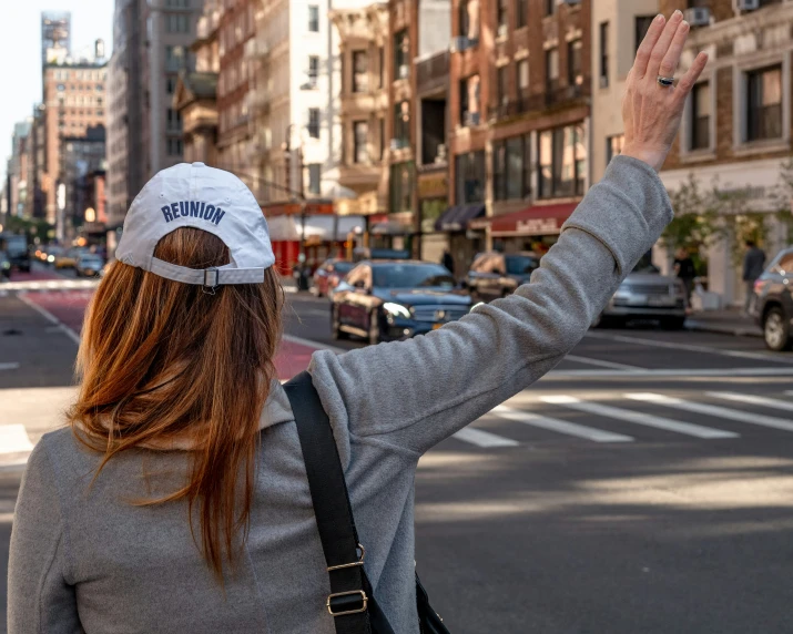 a woman in grey top and white hat standing on street