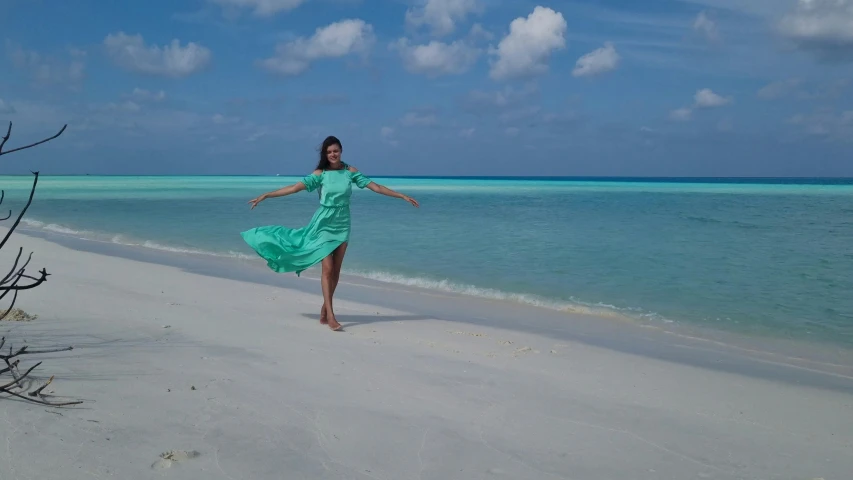 a woman walking along the beach in a green dress