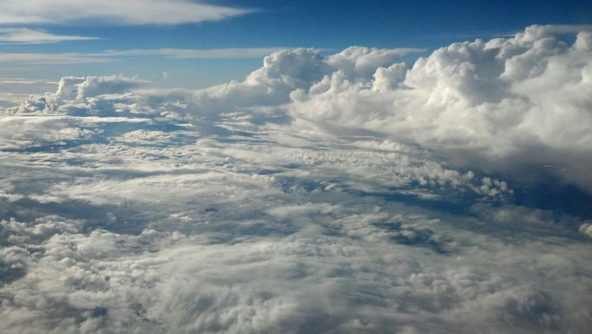 looking out the window of an airplane as it flies in the sky with white clouds