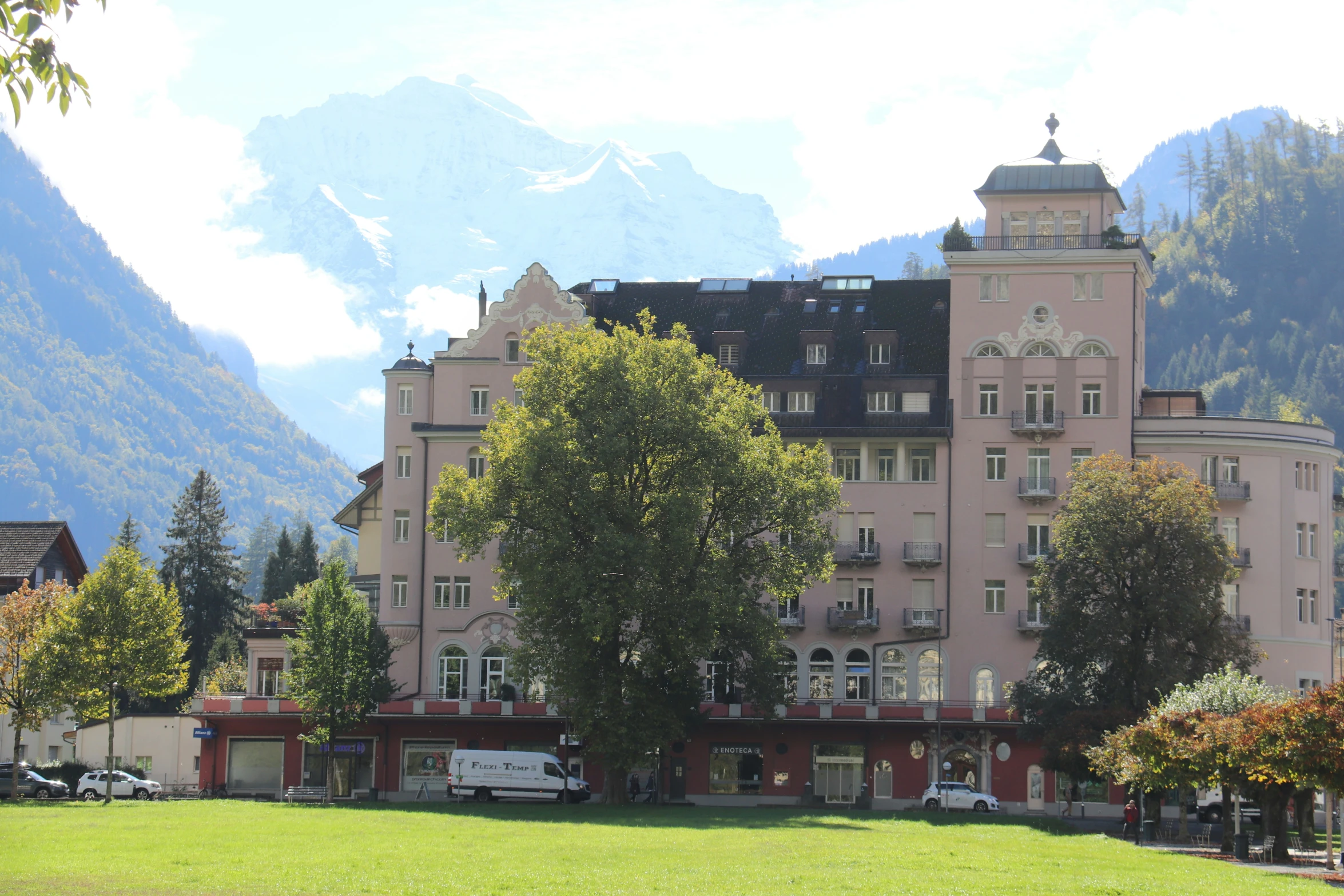 a building with multiple windows sits in front of a mountain