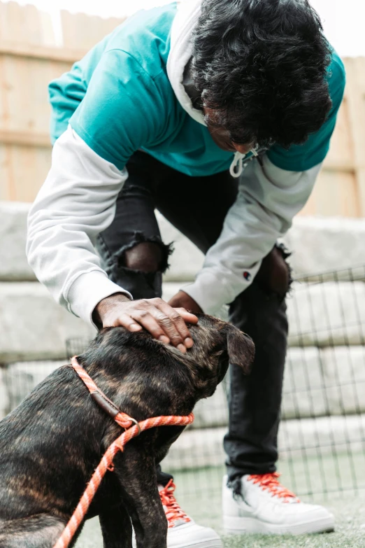 an african american man kneeling down petting a dog