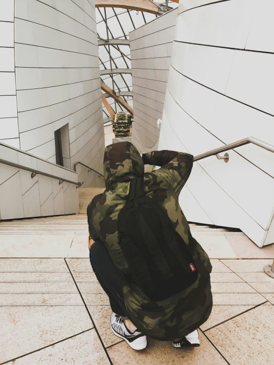 a man is carrying a camouflage bag while sitting down