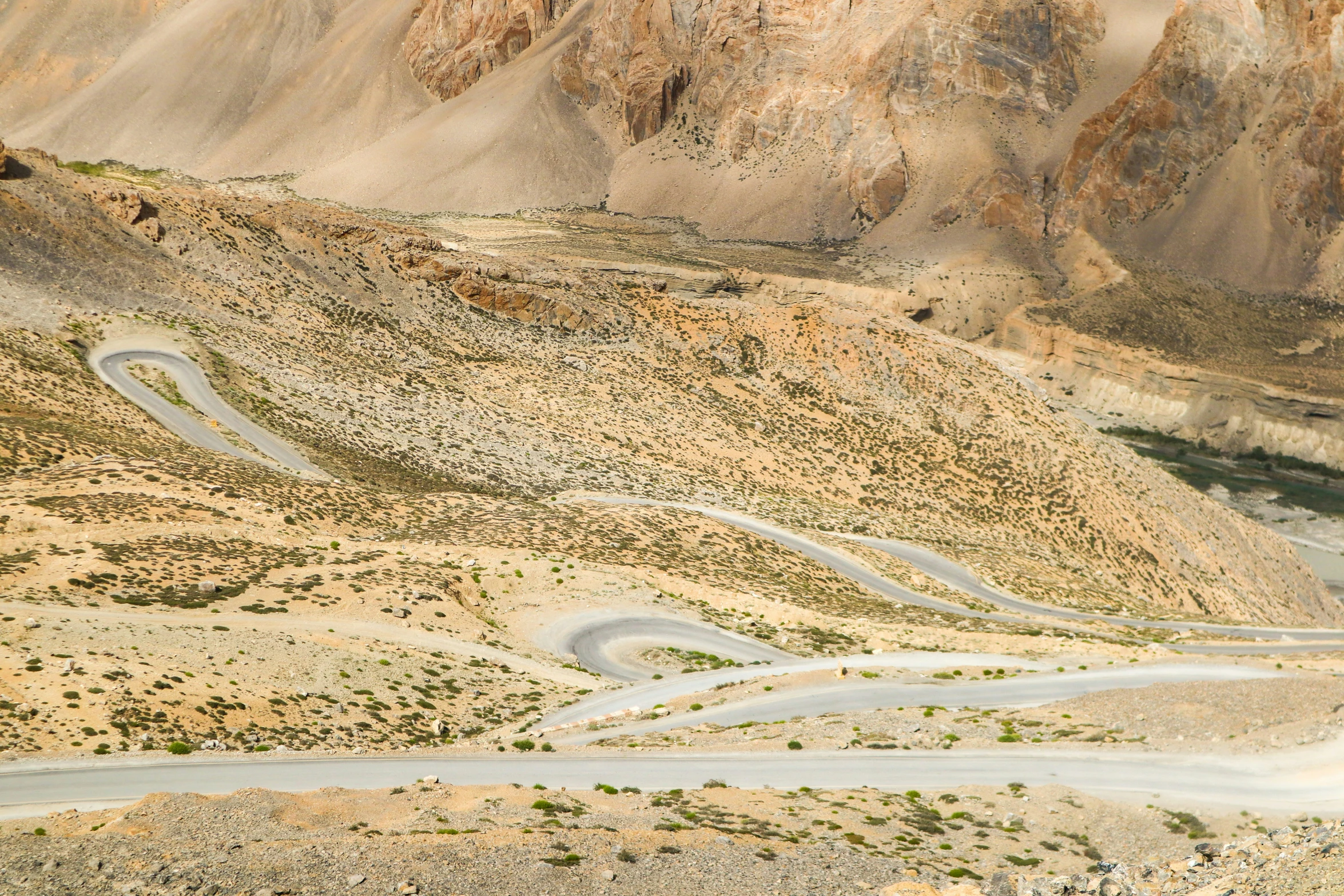 a winding dirt road through a hilly desert landscape