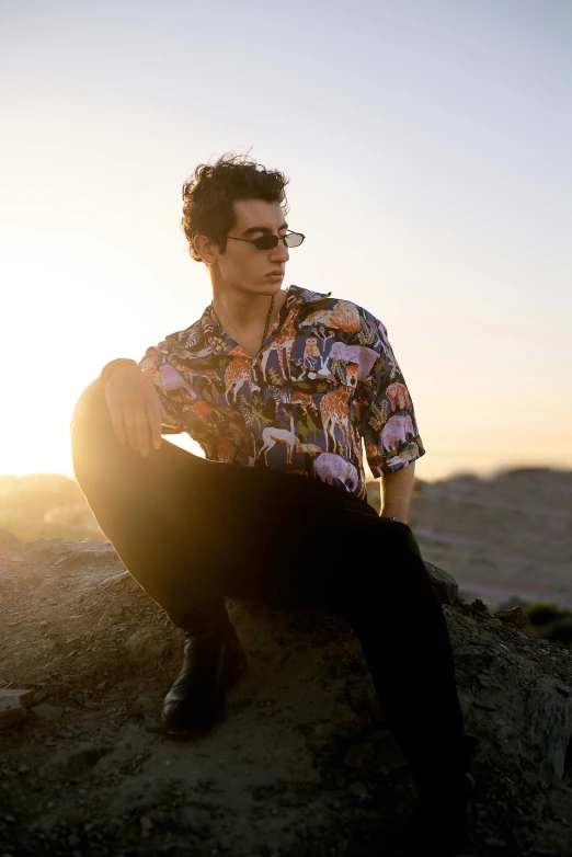 a man with sunglasses is sitting on a rock