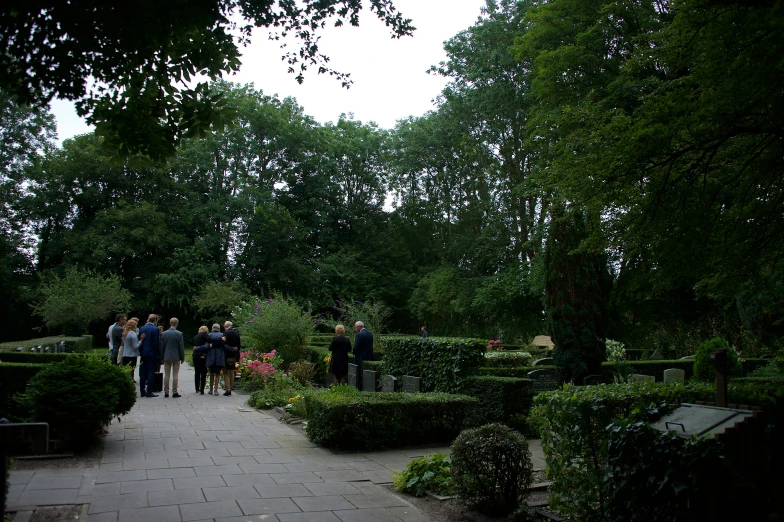 there is a group of people standing on a walkway in a garden