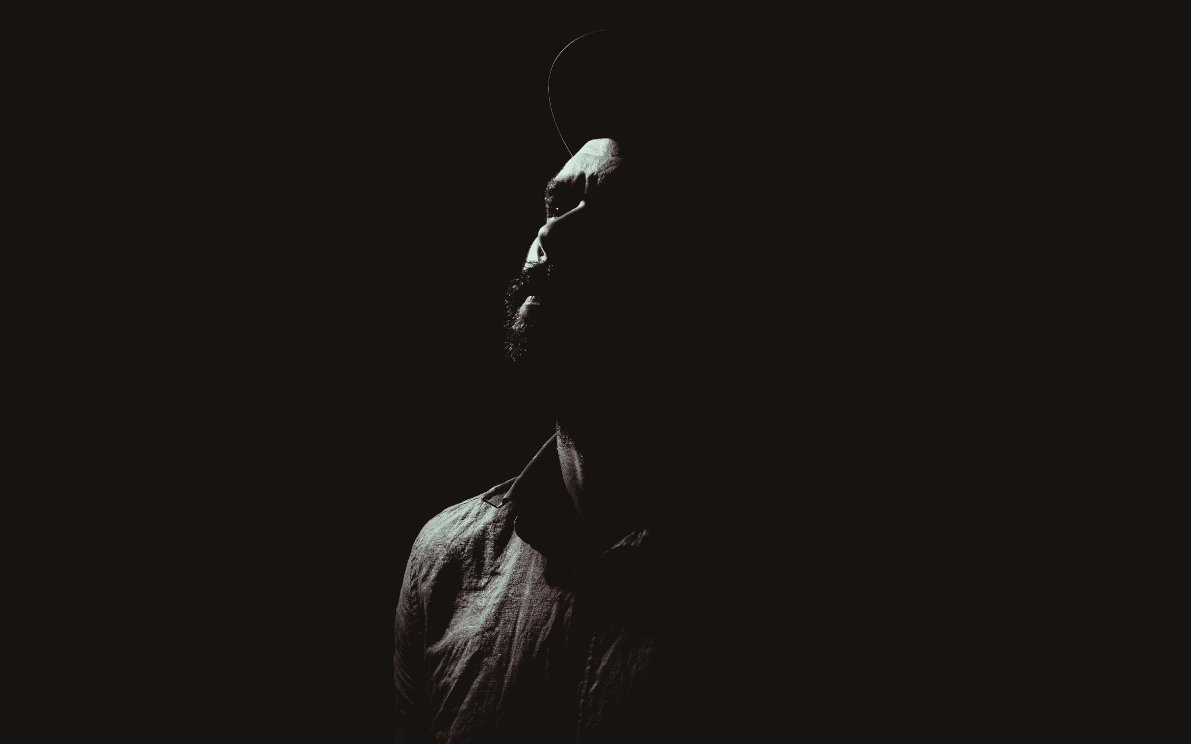 a man standing alone in the dark with his back turned to the camera