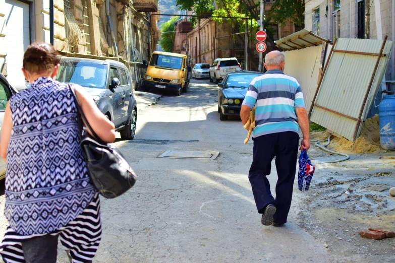 an elderly couple stroll down a small street