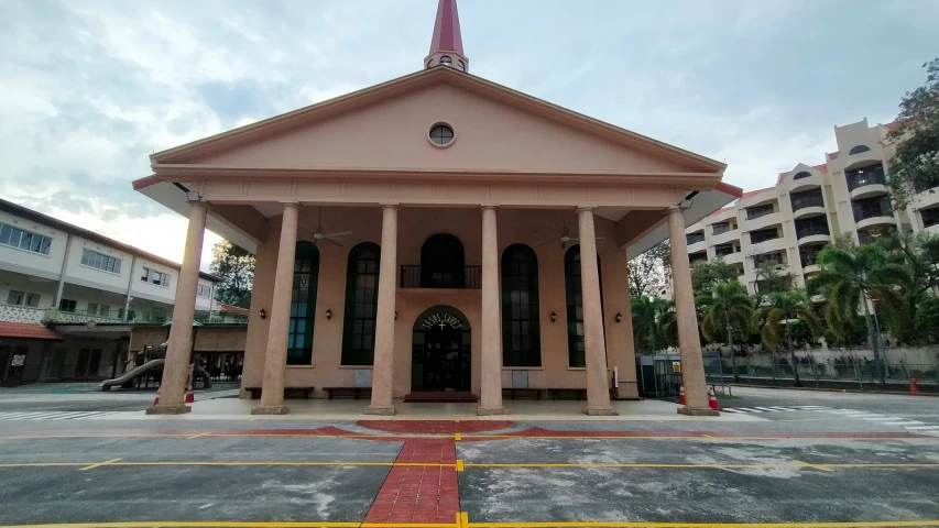 an old church with pillars sits in a parking lot