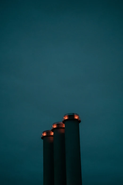 three black metal cylindrical buildings with candles near each other