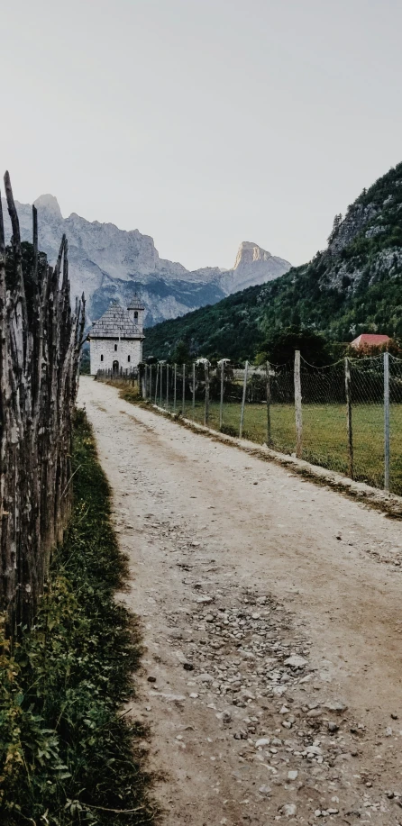 the dirt road is near the fence on a mountain side