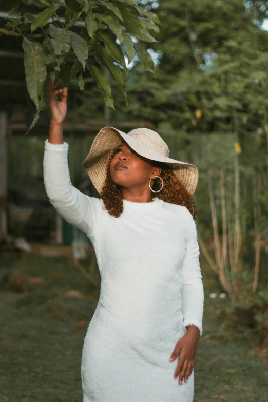 a woman standing and reaching up to a leaf