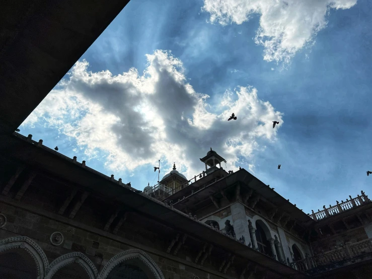 birds flying by a tower structure with some clouds