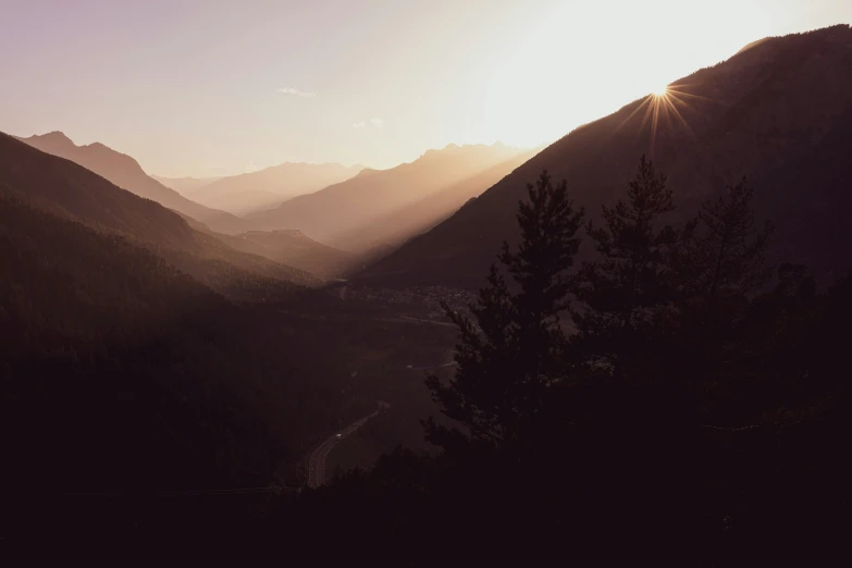 a scenic s of a mountain range with the sun behind the mountains