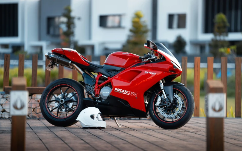 a red motorcycle is parked by a fence