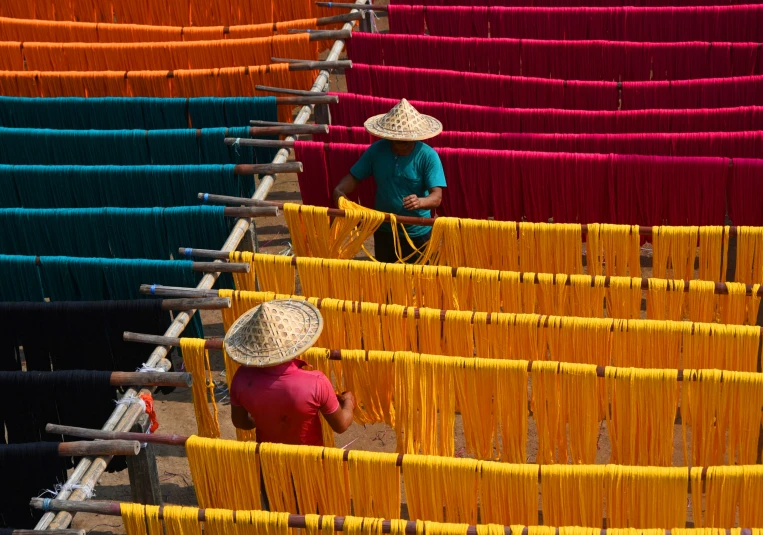 two women in hats are working on weaving