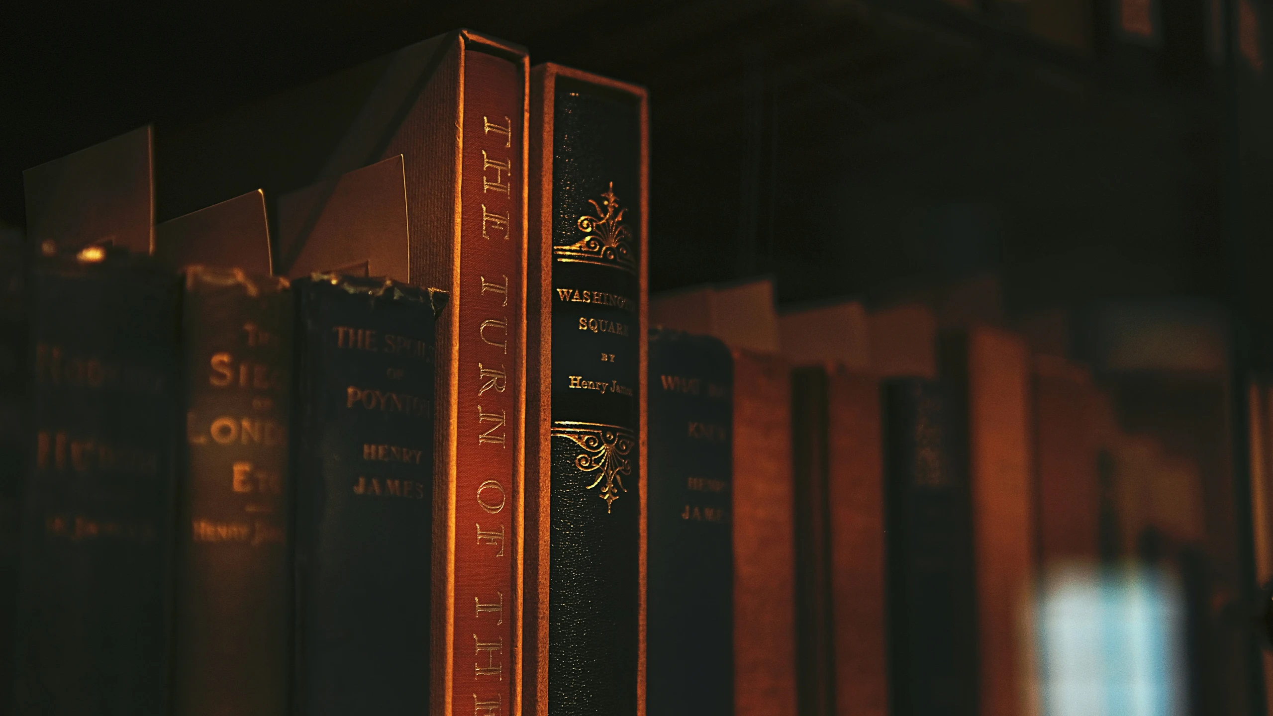 three brown bookshelves, in a dark room