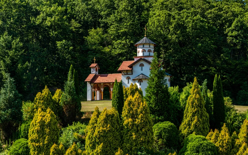 a church tower among trees in front of mountains
