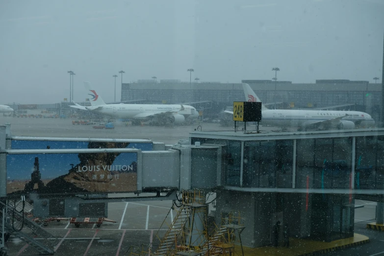 an airport during a winter storm with planes parked