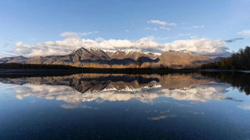 a mountain reflection with pine trees and mountains in the background