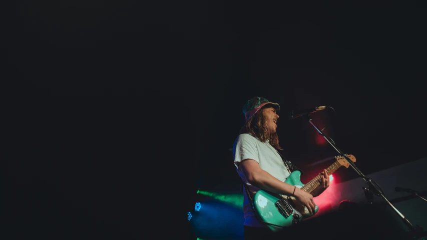 man in green and white shirt playing a guitar