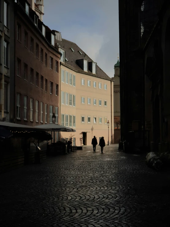 two people walk down the cobblestone streets of an old european town