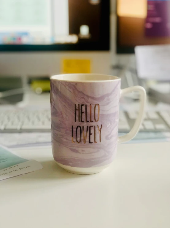 a purple cup sitting on top of a computer desk