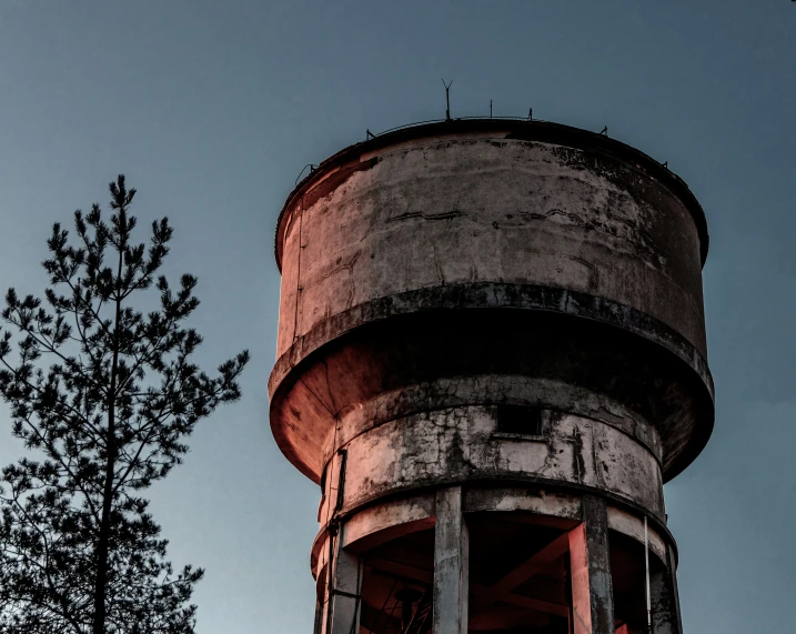 a weathered looking tower with trees and sky in the background