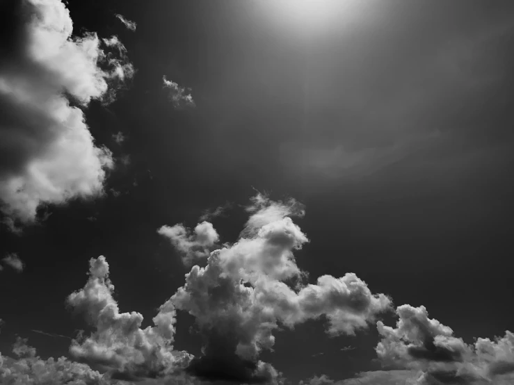 a sun shines through a black and white sky with clouds