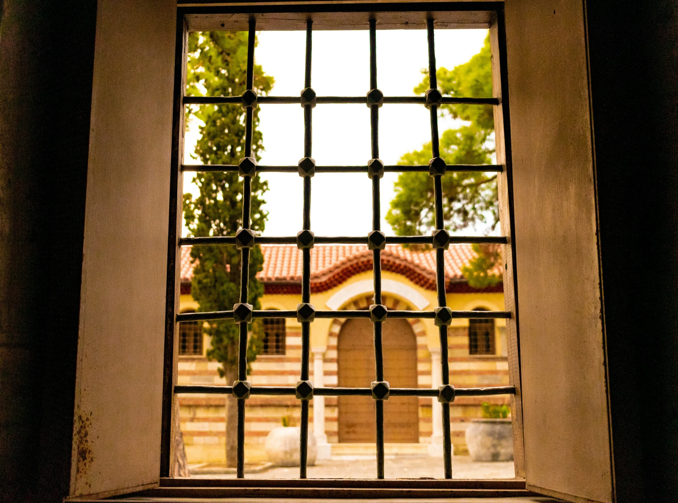 a window that has bars on it and some trees outside