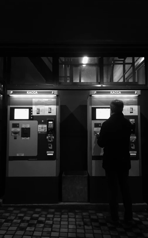 a man standing next to atm machines at night
