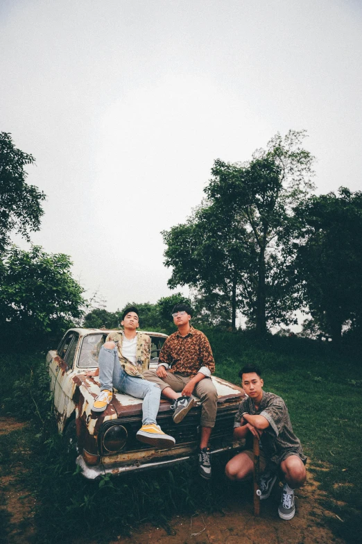 three guys sitting on the back of an old pickup truck