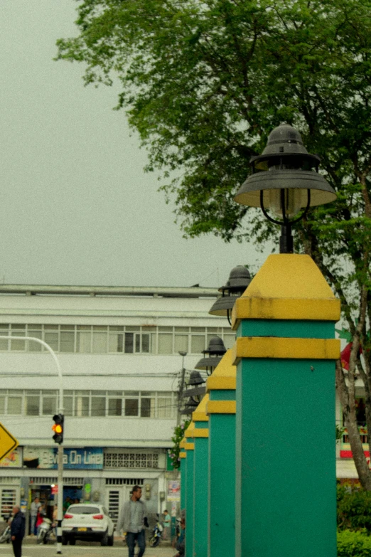 a street light with green and yellow posts and a yellow arrow sign on top