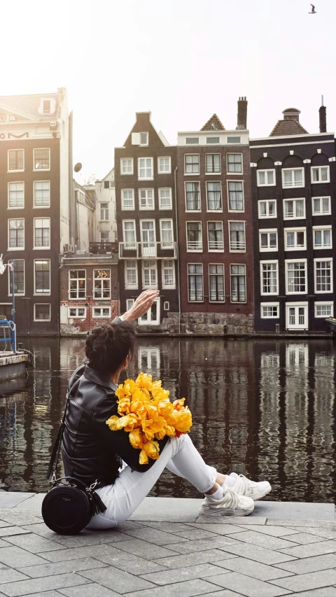 woman sitting on pier with flower bouquet in front of buildings