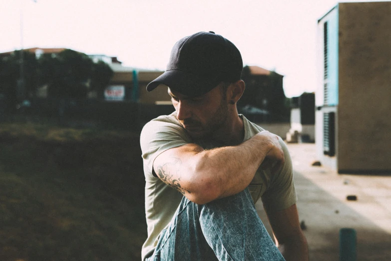 the man is in jeans and cap leaning against the wall