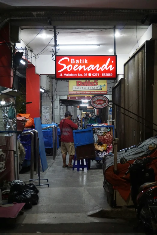 an alley in a chinese market with a man standing by a large sign