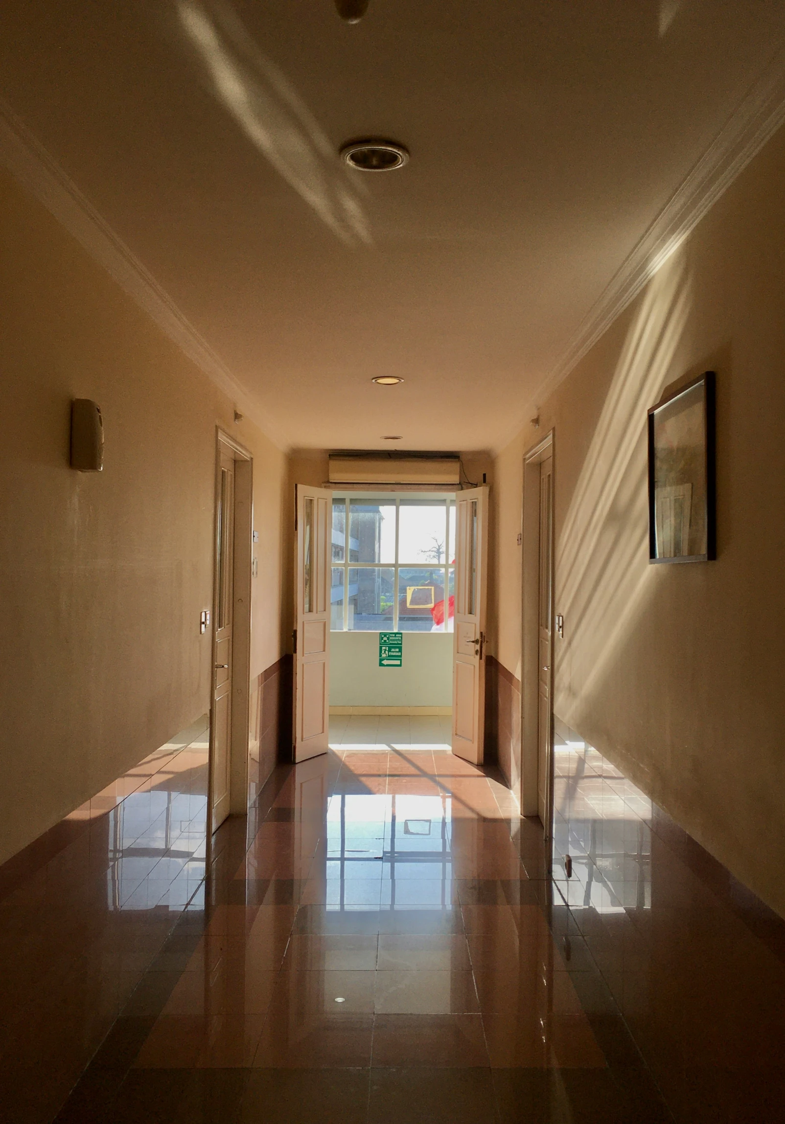 long hallway in an apartment building with empty doors and glass floors